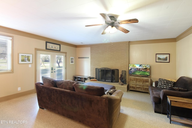 living room featuring a brick fireplace, light colored carpet, crown molding, and french doors