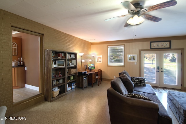 living room with ceiling fan, french doors, and brick wall