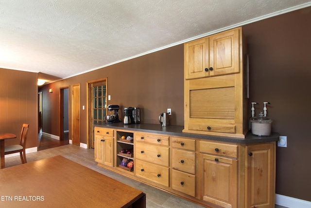 kitchen featuring a textured ceiling, crown molding, and light tile patterned floors