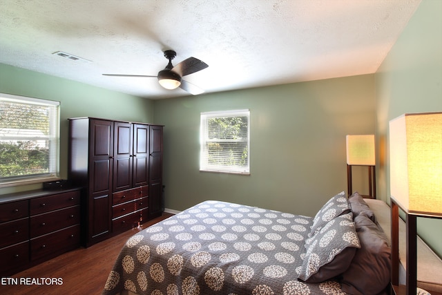 bedroom featuring ceiling fan, dark hardwood / wood-style floors, and a textured ceiling