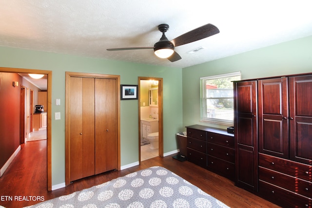 bedroom featuring ceiling fan, a textured ceiling, a closet, ensuite bath, and dark hardwood / wood-style flooring