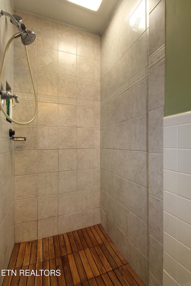 bathroom featuring a tile shower, hardwood / wood-style floors, and tile walls