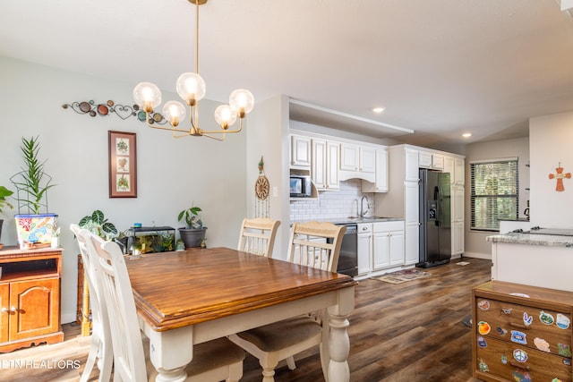 dining room with dark wood-type flooring, a notable chandelier, and sink