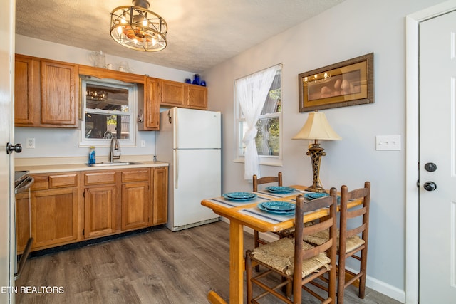 kitchen with sink, a textured ceiling, dark wood-type flooring, a notable chandelier, and white refrigerator