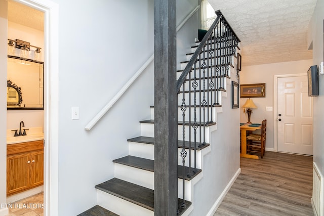 stairway featuring hardwood / wood-style flooring, a textured ceiling, and sink