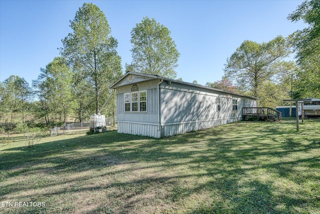 view of side of property featuring a wooden deck and a lawn