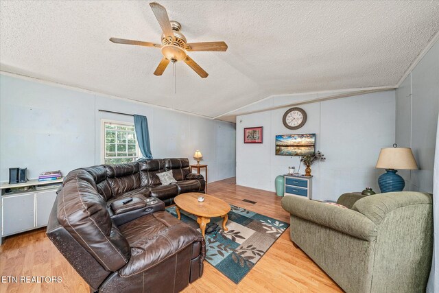 living room with lofted ceiling, a textured ceiling, light hardwood / wood-style floors, and ceiling fan