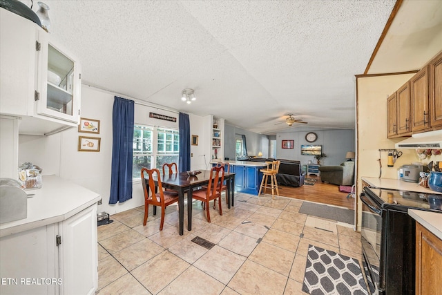 dining space featuring a textured ceiling, ceiling fan, light tile patterned flooring, and vaulted ceiling