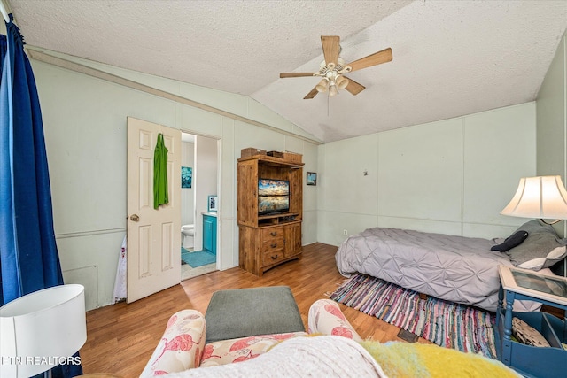 bedroom featuring lofted ceiling, ceiling fan, a textured ceiling, light wood-type flooring, and ensuite bathroom