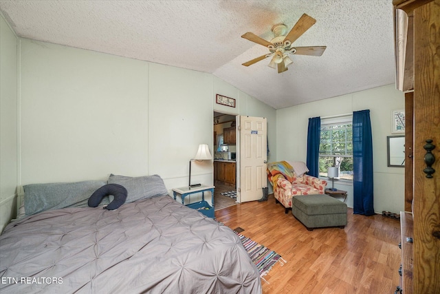 bedroom with ceiling fan, wood-type flooring, a textured ceiling, and vaulted ceiling