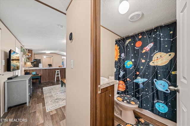 bathroom featuring toilet, wood-type flooring, vaulted ceiling, vanity, and a textured ceiling