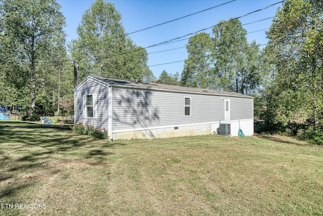 back of house with central air condition unit and a lawn