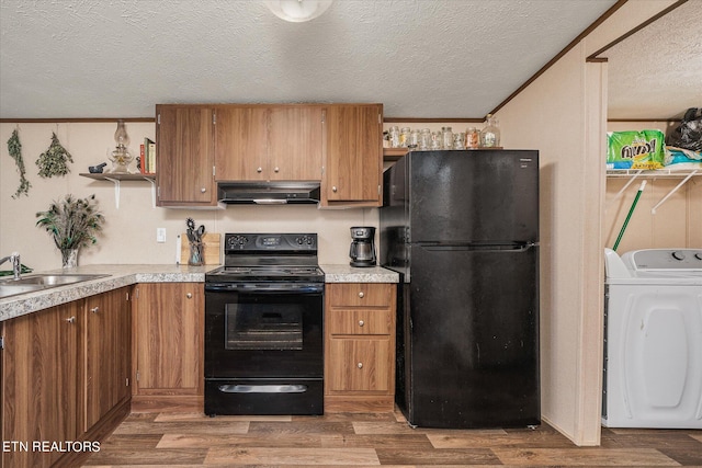 kitchen with washer / dryer, black appliances, sink, a textured ceiling, and hardwood / wood-style flooring