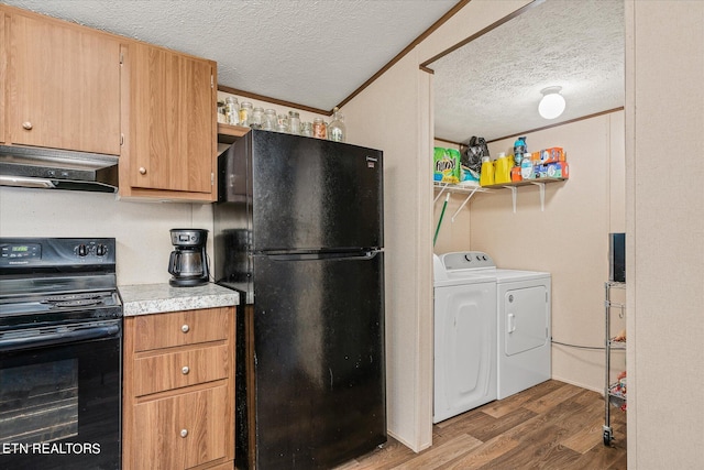 kitchen featuring dark wood-type flooring, range hood, black appliances, crown molding, and washing machine and dryer