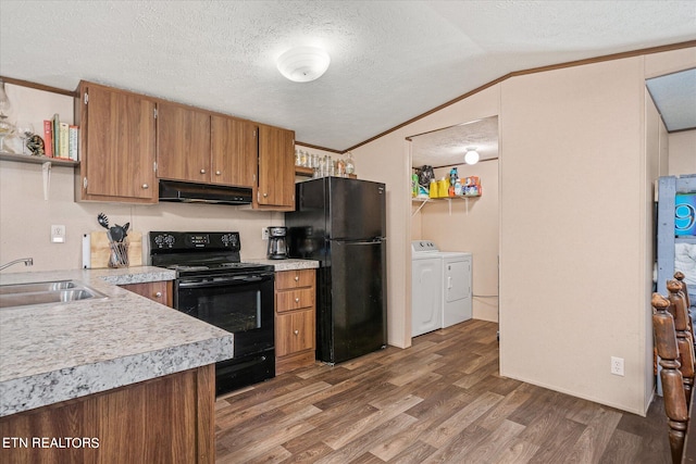 kitchen featuring lofted ceiling, range hood, sink, black appliances, and washer and dryer