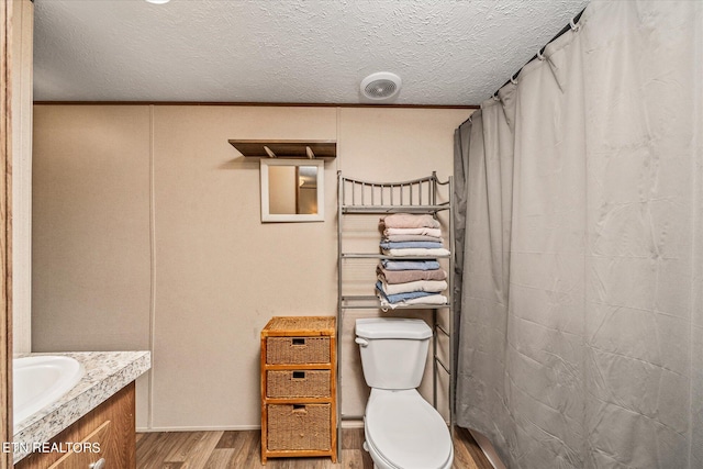 bathroom with toilet, hardwood / wood-style floors, curtained shower, vanity, and a textured ceiling