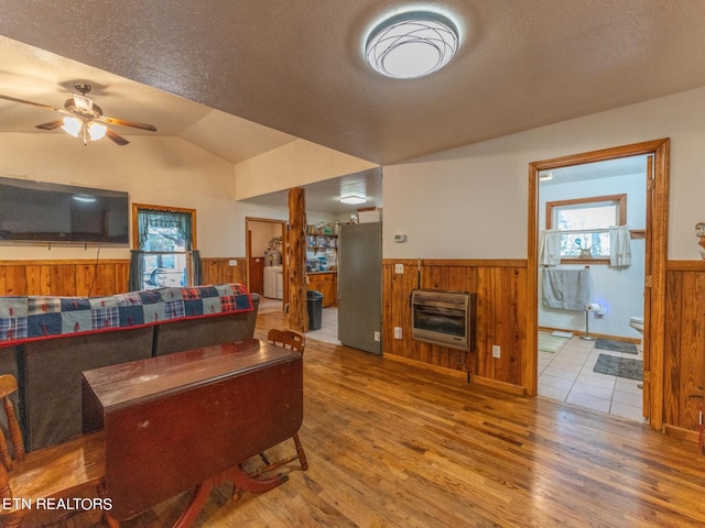 living room with lofted ceiling, wood walls, hardwood / wood-style floors, and heating unit