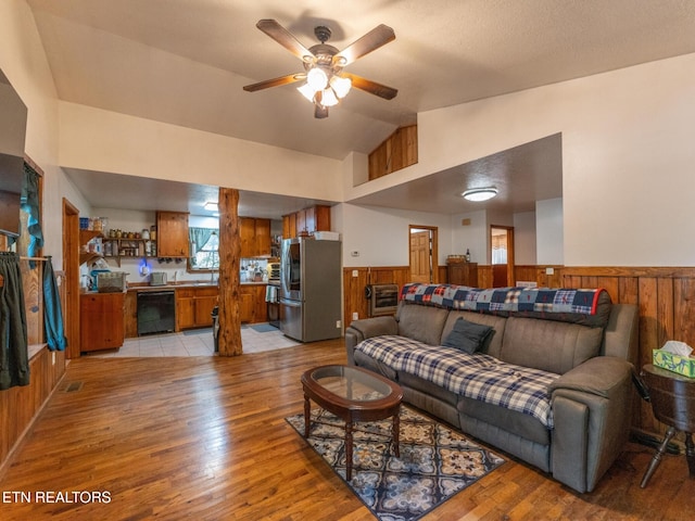 living room with light wood-type flooring, wood walls, and vaulted ceiling