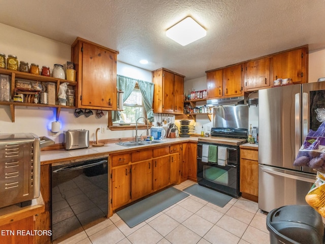 kitchen with light tile patterned floors, a textured ceiling, sink, and black appliances