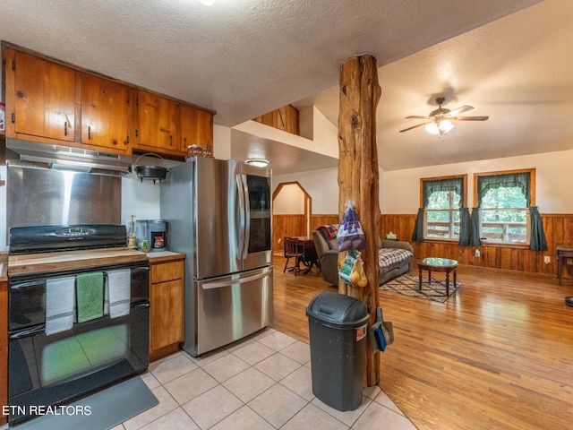 kitchen featuring stainless steel fridge, light wood-type flooring, black stove, and vaulted ceiling