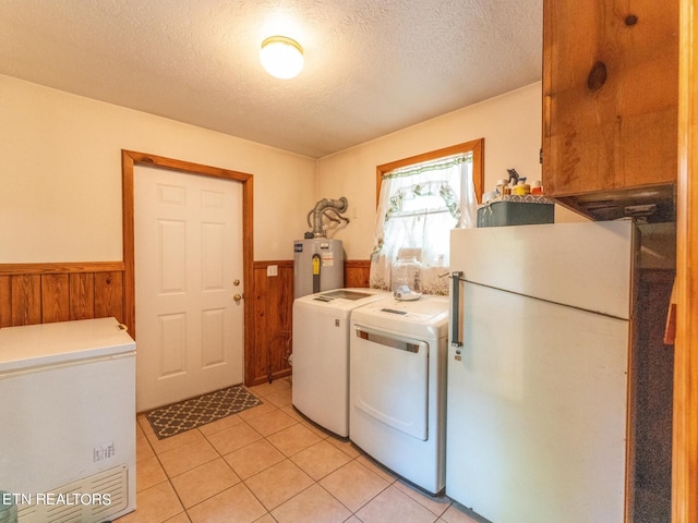 clothes washing area with washing machine and clothes dryer, wood walls, water heater, and a textured ceiling