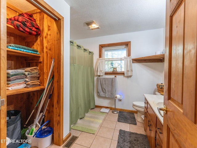 bathroom with vanity, toilet, a textured ceiling, tile patterned flooring, and a shower with shower curtain