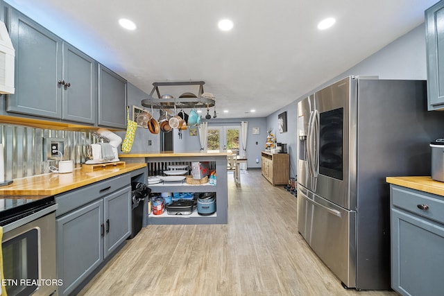 kitchen with wooden counters, stainless steel appliances, light hardwood / wood-style floors, and tasteful backsplash