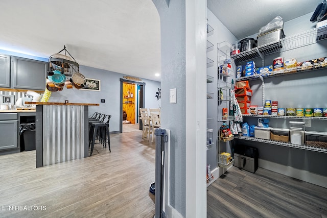 interior space featuring a breakfast bar area, wood-type flooring, and gray cabinetry