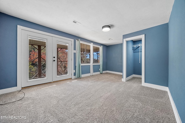 unfurnished bedroom featuring french doors, a textured ceiling, and carpet flooring