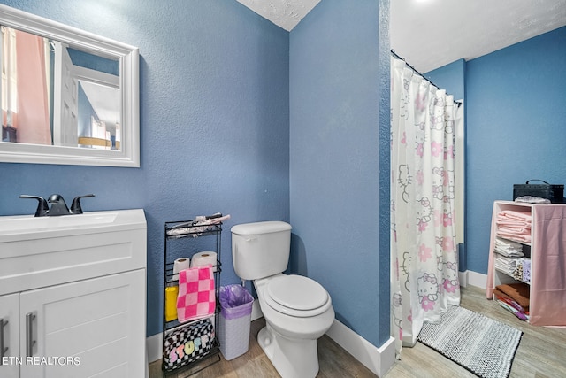 bathroom featuring curtained shower, a textured ceiling, hardwood / wood-style floors, toilet, and vanity