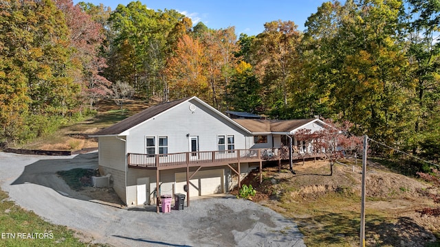 rear view of house featuring a deck, central AC unit, and a garage