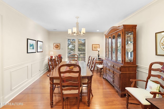 dining space with a notable chandelier, ornamental molding, and light wood-type flooring