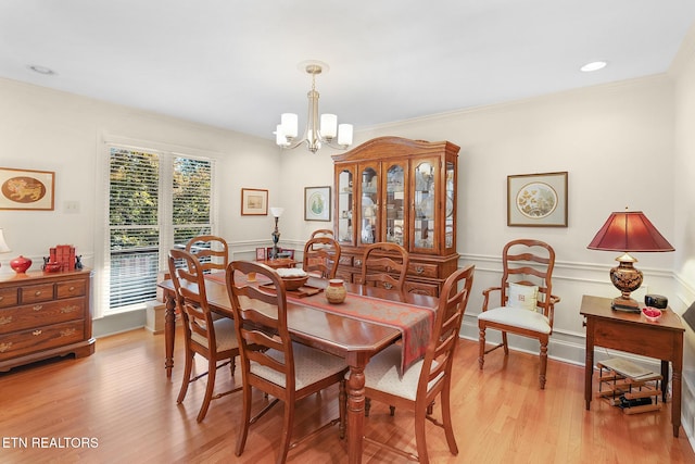 dining area with ornamental molding, a chandelier, and light hardwood / wood-style flooring