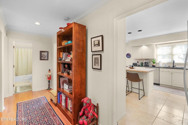 corridor featuring sink, ornamental molding, and light tile patterned floors