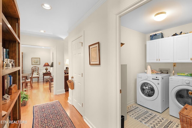 washroom with light hardwood / wood-style floors, washing machine and dryer, cabinets, and ornamental molding