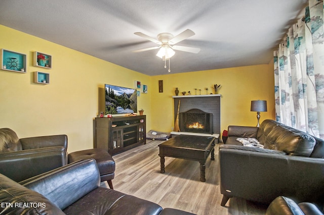 living room with a fireplace, light hardwood / wood-style floors, and ceiling fan