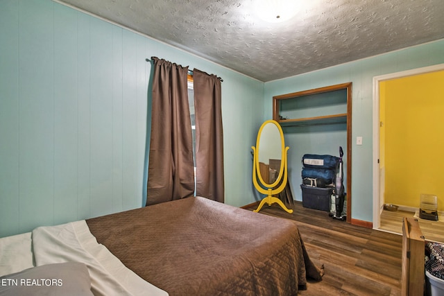 bedroom featuring a textured ceiling, dark hardwood / wood-style floors, and a closet