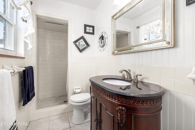 bathroom featuring toilet, tile walls, tiled shower, vanity, and tile patterned flooring