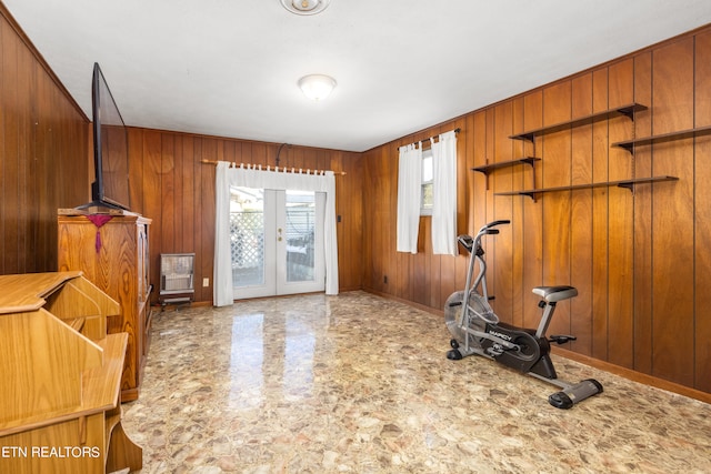 exercise area featuring french doors, a healthy amount of sunlight, and wood walls