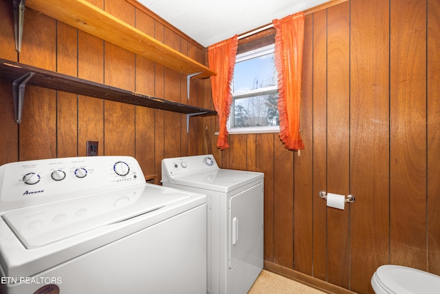 laundry room featuring washer and dryer and wood walls