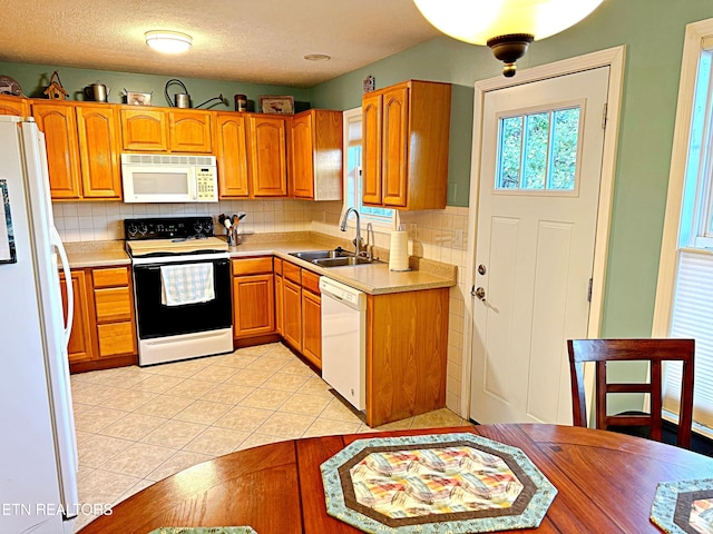 kitchen with backsplash, a textured ceiling, white appliances, sink, and light tile patterned flooring