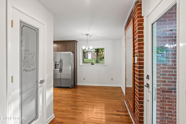 kitchen featuring pendant lighting, a notable chandelier, wood-type flooring, and stainless steel refrigerator with ice dispenser