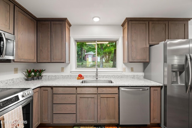 kitchen with stainless steel appliances, light stone counters, and sink