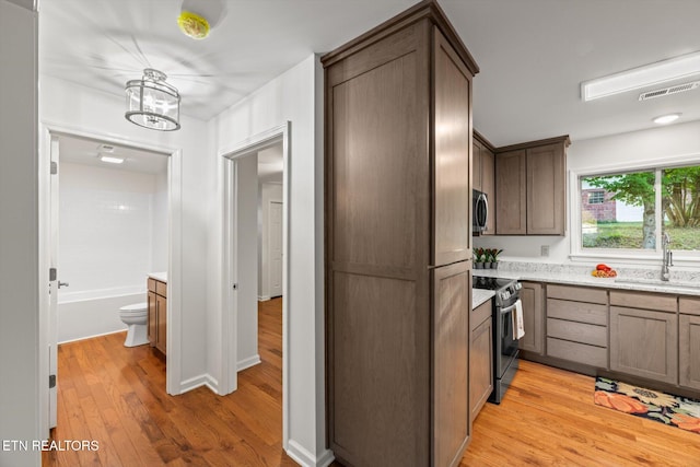 kitchen with sink, light hardwood / wood-style flooring, decorative light fixtures, and appliances with stainless steel finishes