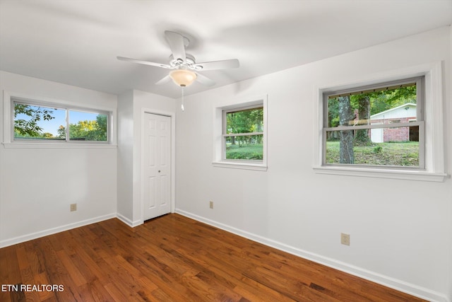 unfurnished bedroom with multiple windows and dark wood-type flooring