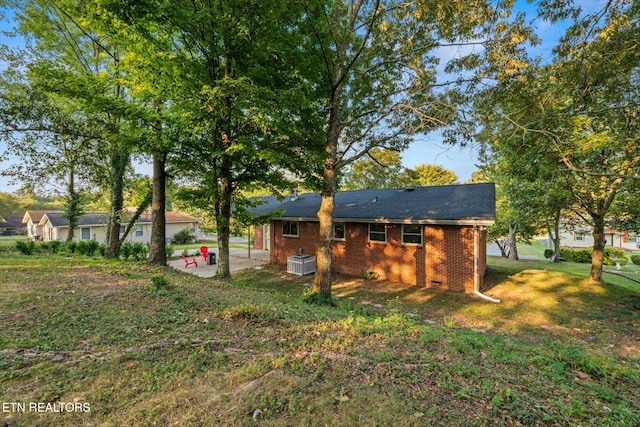 rear view of property with a lawn, a patio area, and central air condition unit