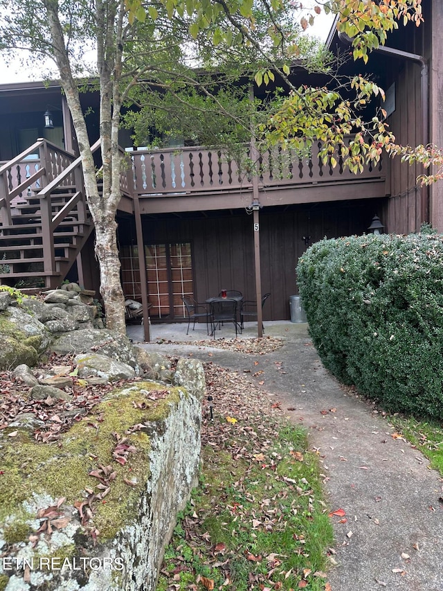 back of property with a wooden deck and a patio