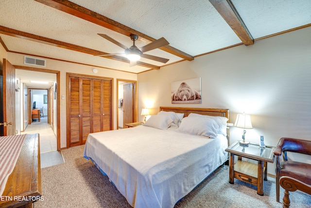 carpeted bedroom featuring a closet, beam ceiling, a textured ceiling, and ceiling fan