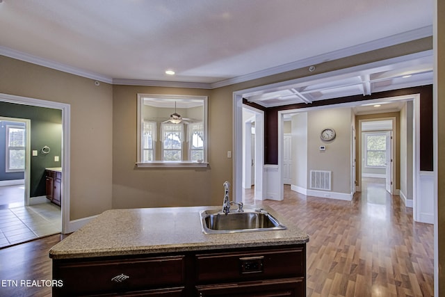 kitchen with coffered ceiling, crown molding, sink, dark brown cabinets, and light hardwood / wood-style floors