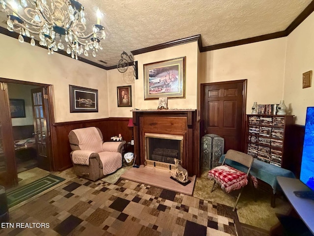 living area with a textured ceiling, crown molding, and wainscoting